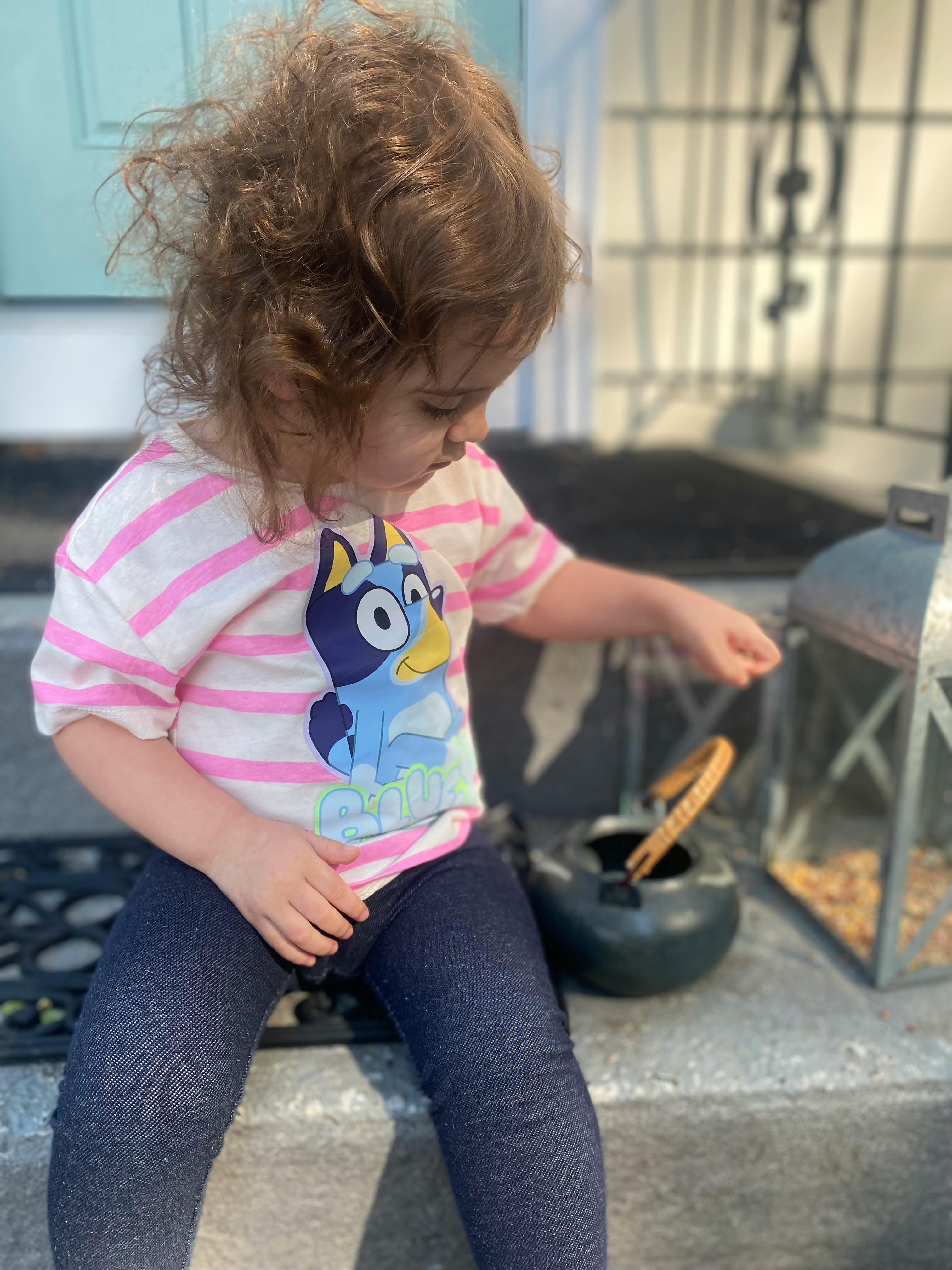 Child in a striped shirt playing with a small pot