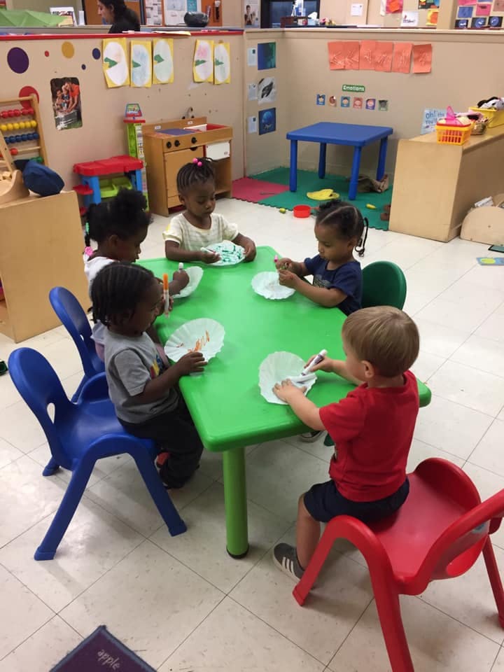 Children sitting at a table doing an art activity in a classroom