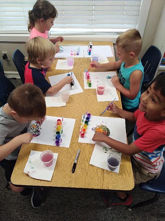 Children painting at a table in a classroom