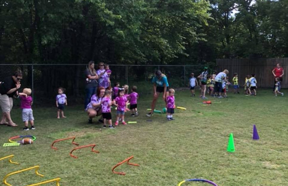 Adults and children gathered in a grassy outdoor area with play equipment