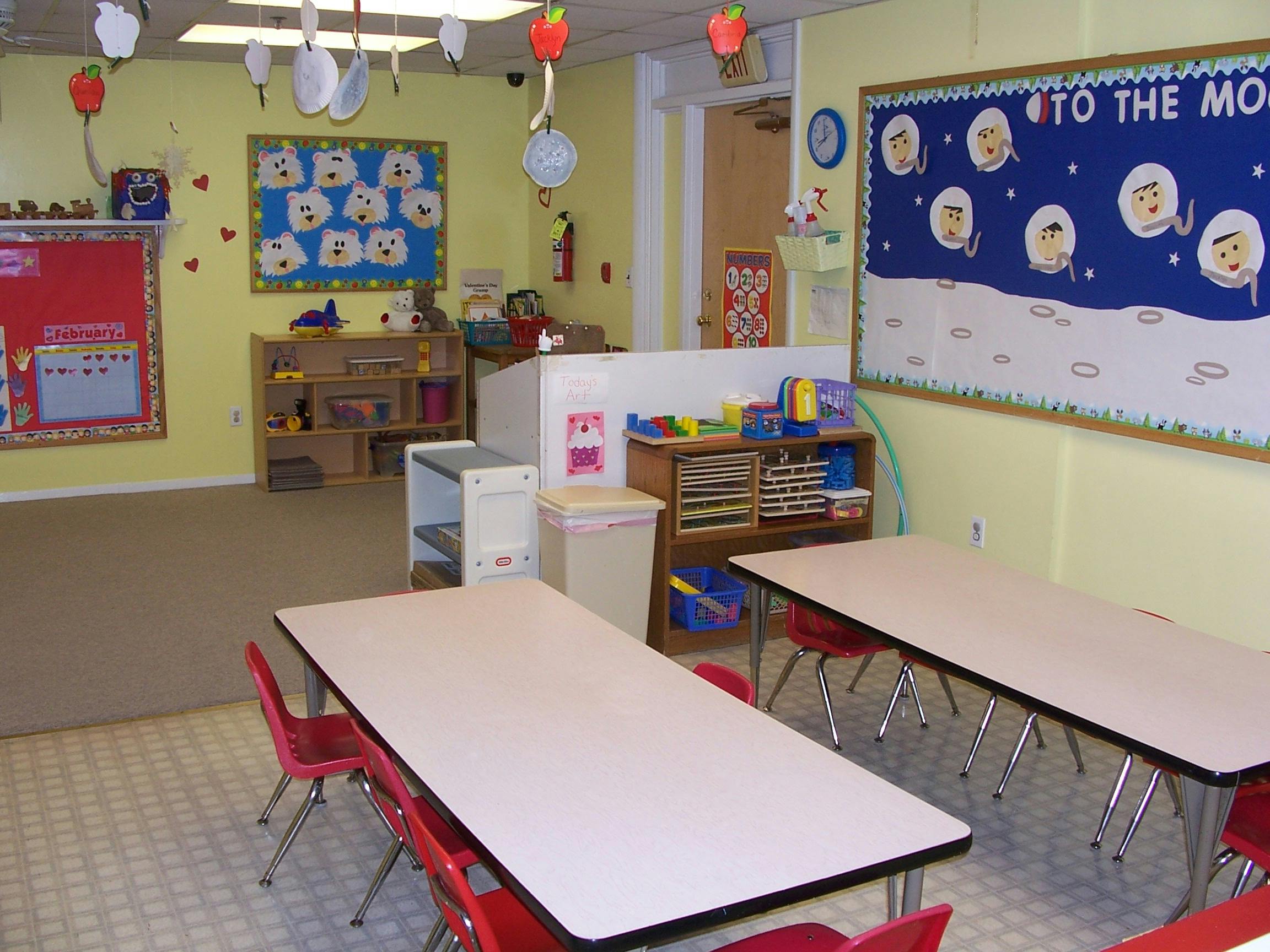 Classroom with tables and chairs, bulletin boards, and storage shelves