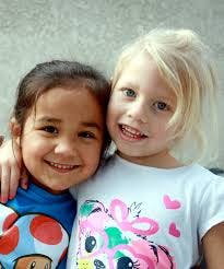 Two children smiling with arms around each other