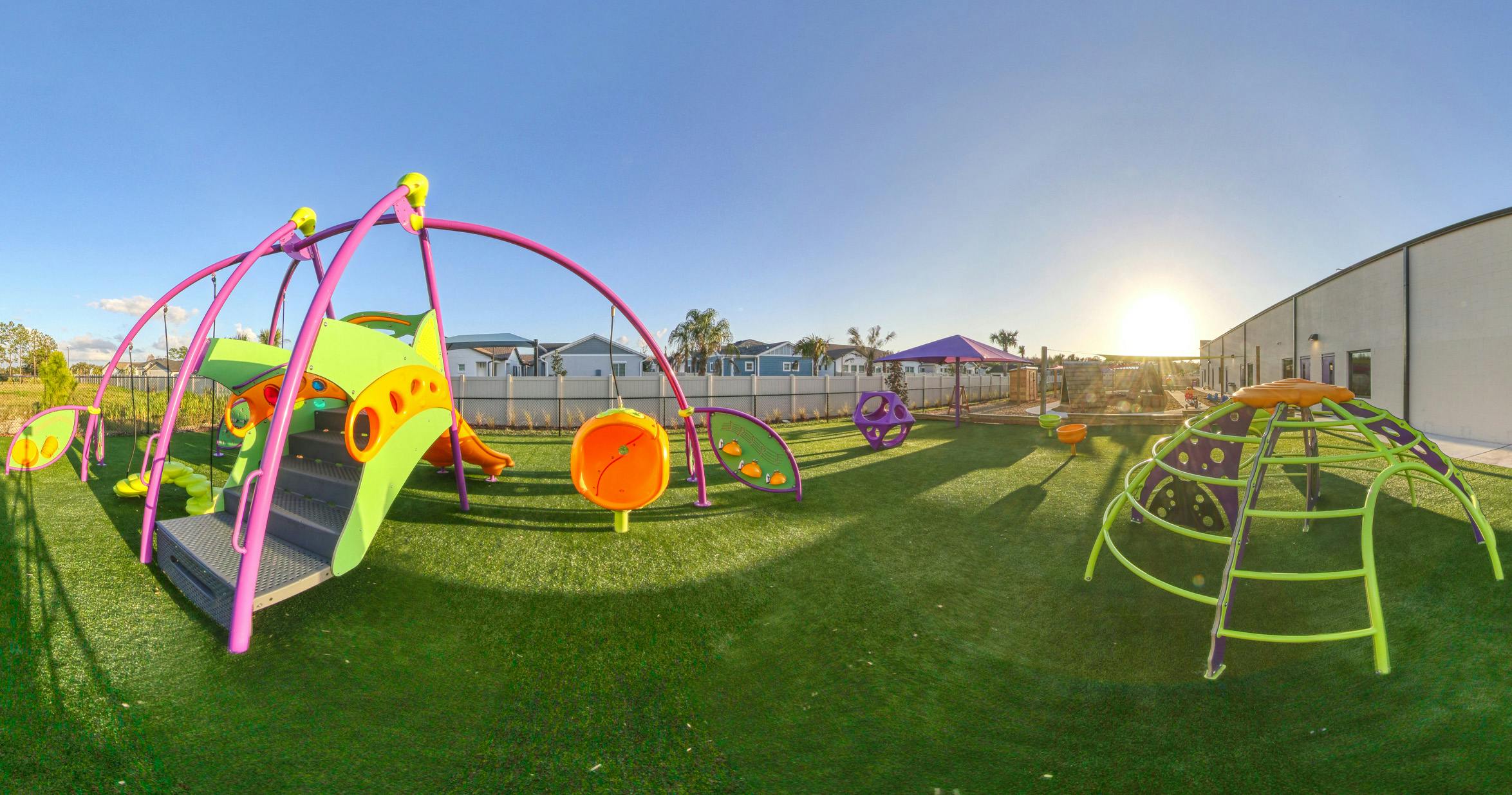 Colorful outdoor playground with slides, swings, and climbing structures on artificial turf