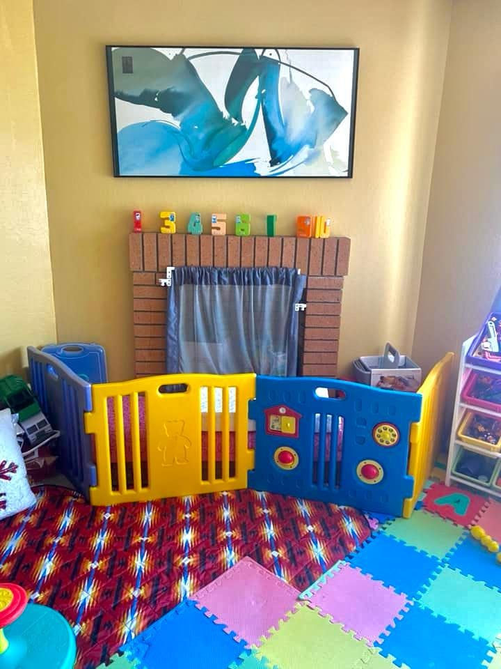Play area with colorful playpen, foam mats, and a fireplace with number blocks