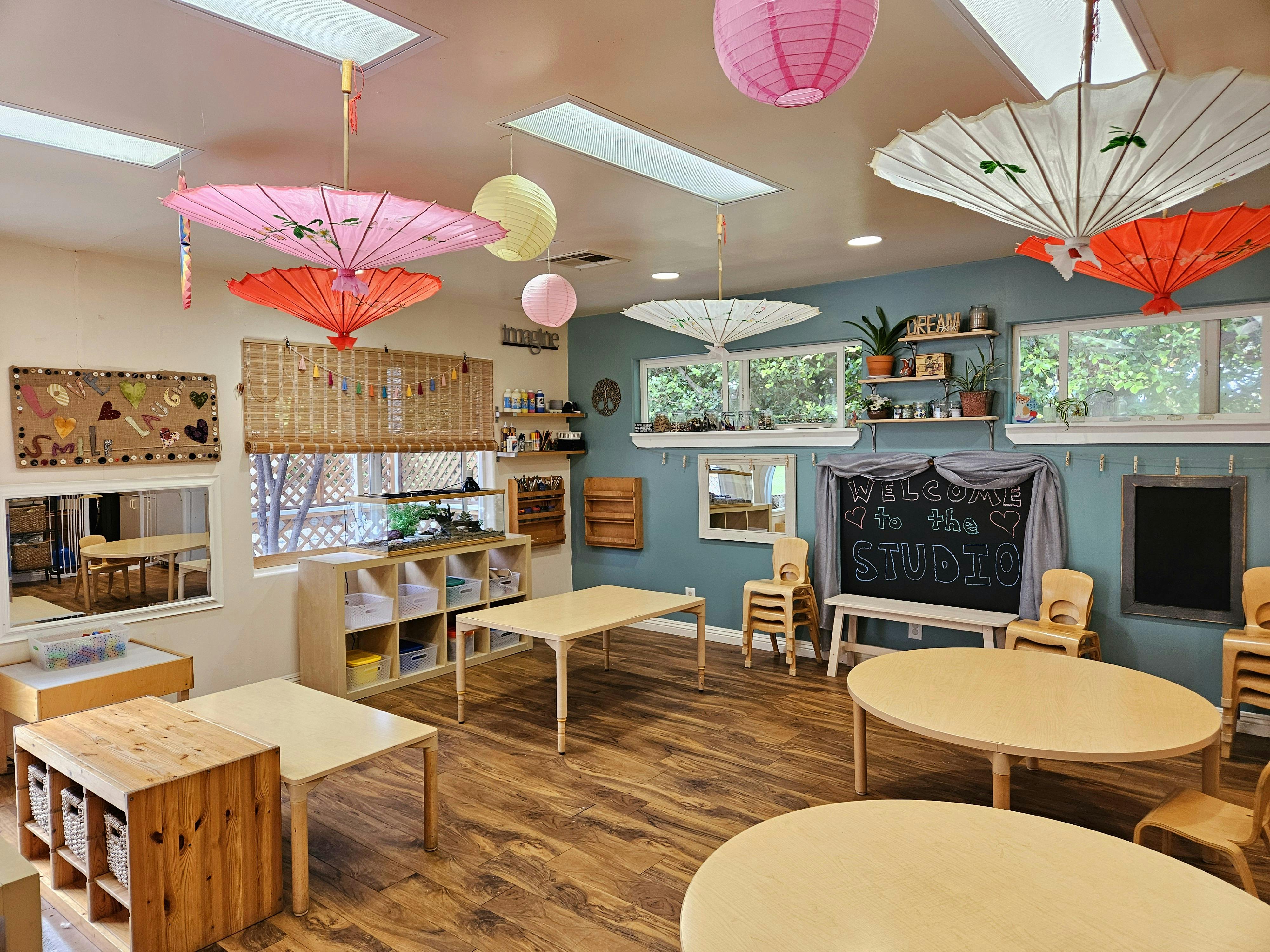 Classroom with small tables and chairs, decorated with paper lanterns and umbrellas
