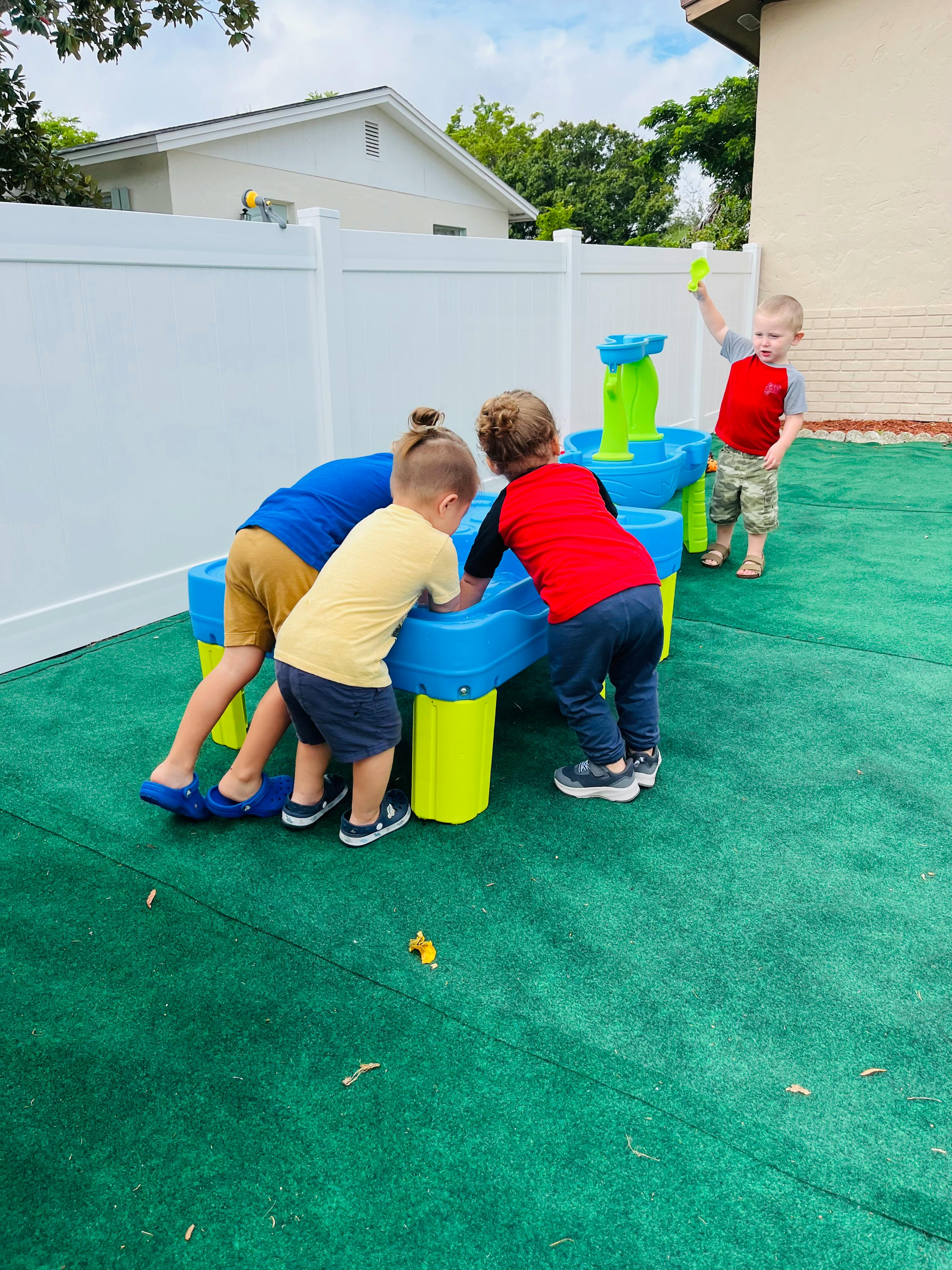 Three children playing at a water table outdoors