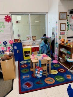 classroom with small table and chairs on an alphabet rug