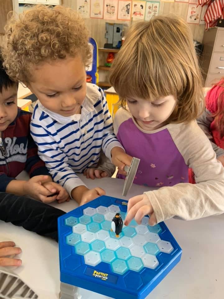 Children playing a board game with a penguin figure