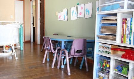 Child's room with small table and chairs, crib, and storage shelves
