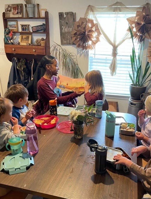 Person reading a book to children at a table