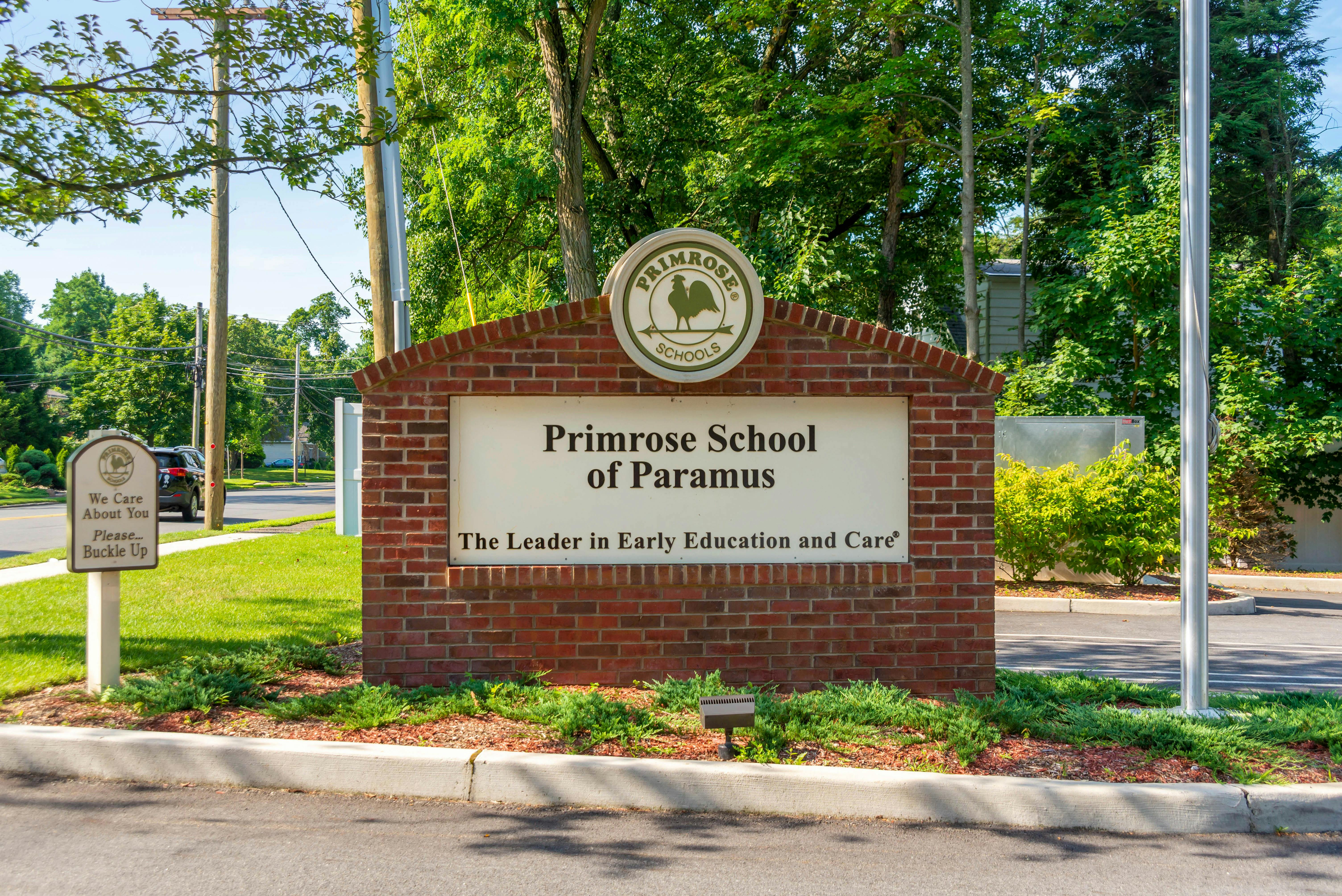 Primrose School of Paramus sign on a brick base with green bushes