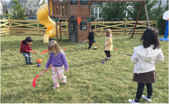 Children playing with toy hockey sticks in a grassy yard