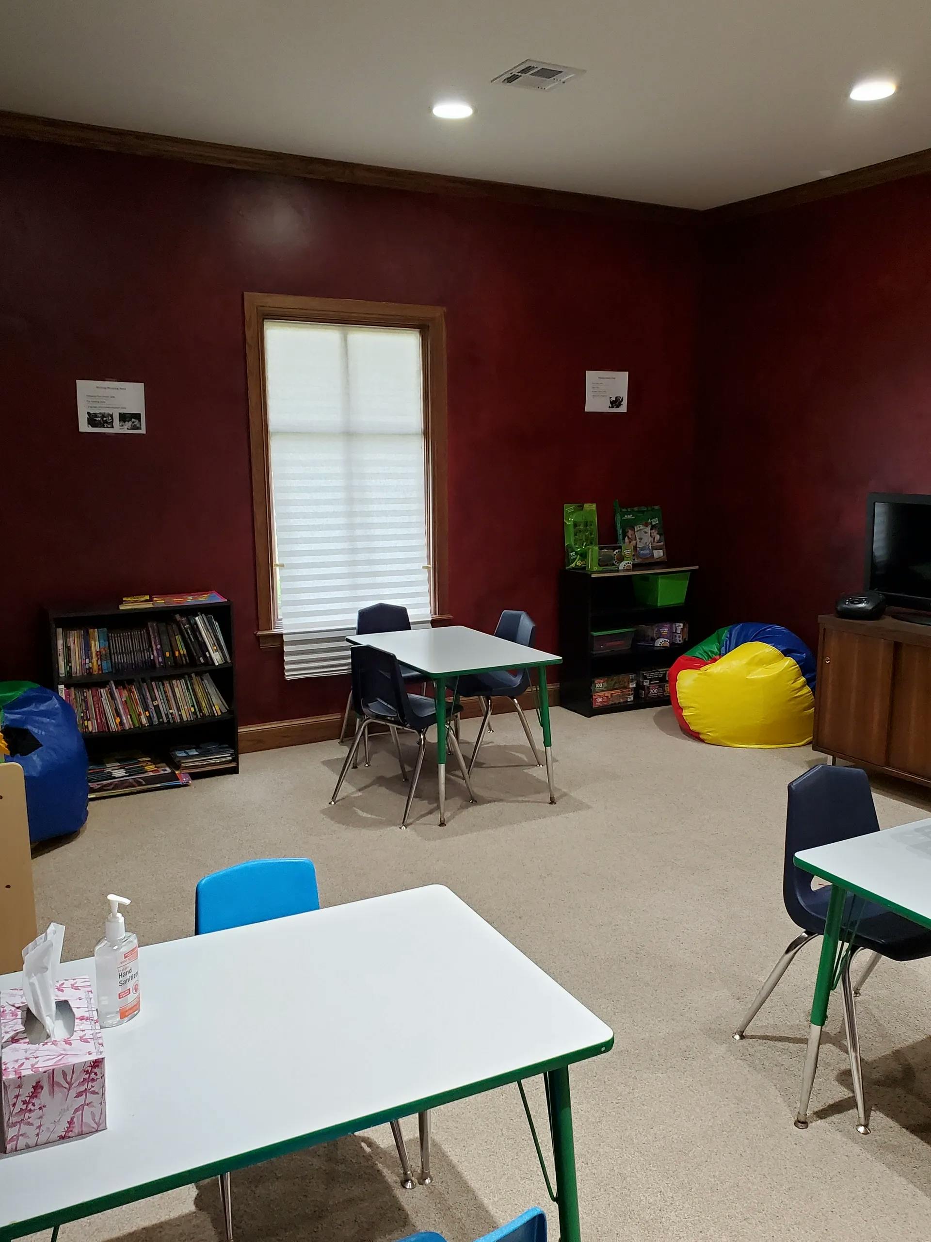 Classroom with tables, chairs, bookshelves, and a window