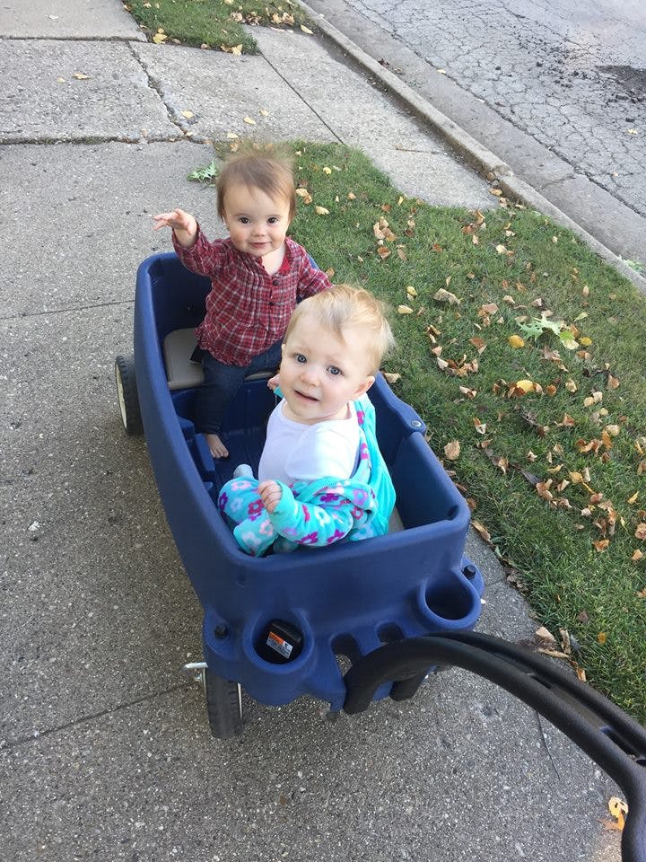 Two children in a blue wagon on a sidewalk