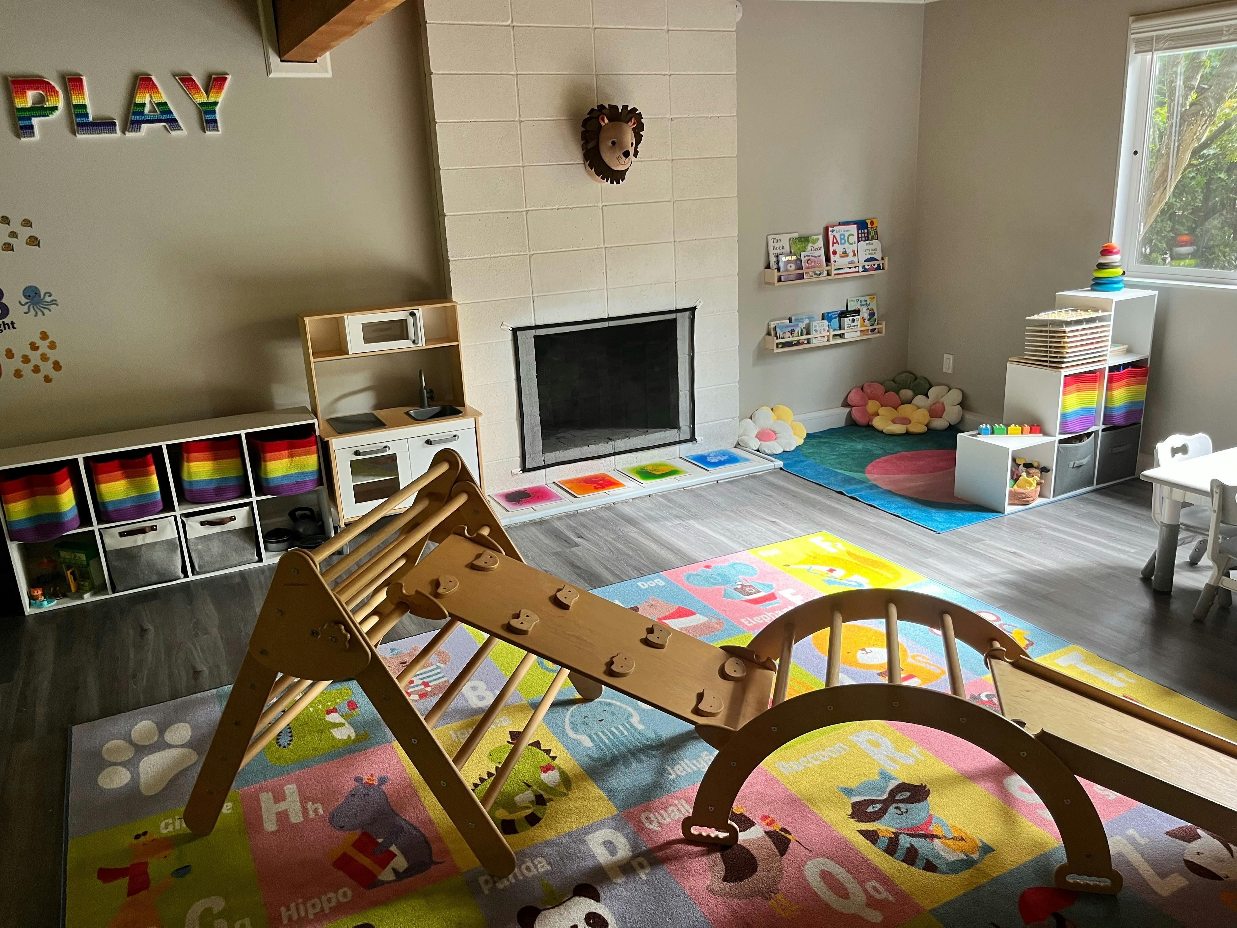 Indoor play area with a wooden climbing structure and colorful mats