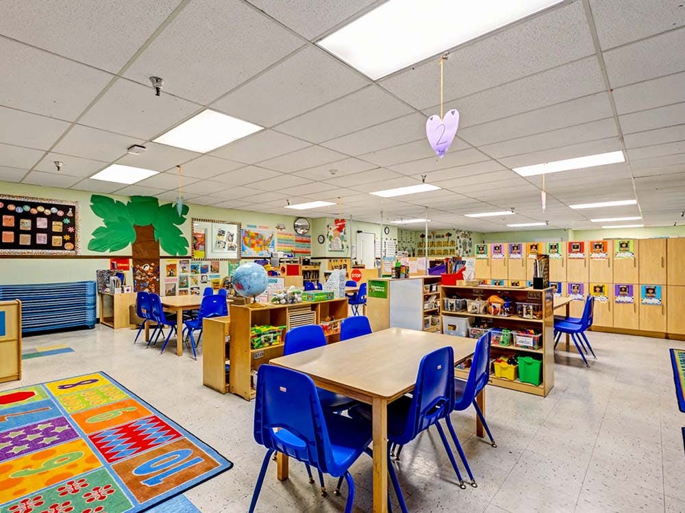 Classroom with small tables, blue chairs, and a colorful rug