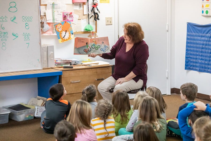 Person reading a book to children in a classroom