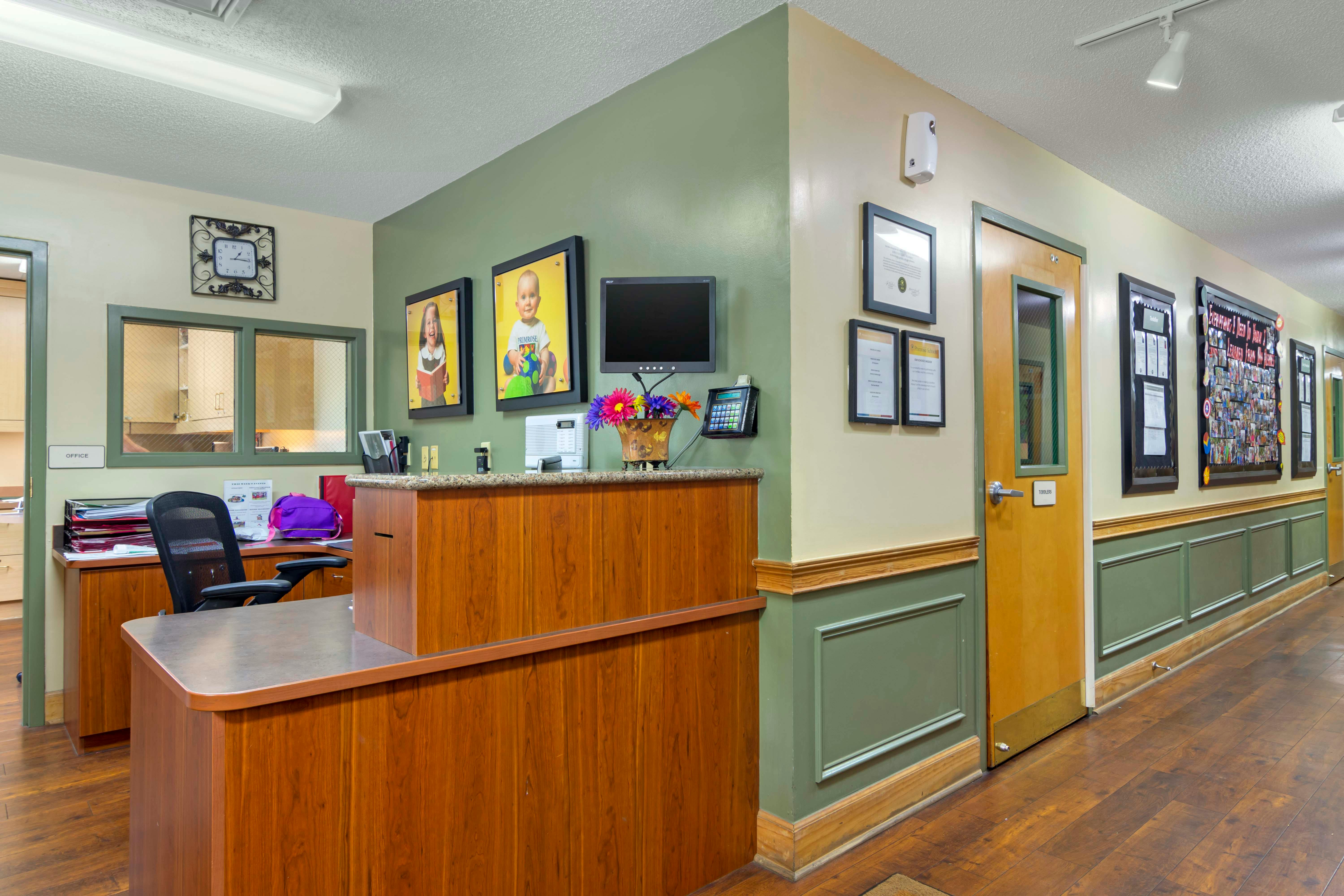 Reception area with a wooden desk, office chair, computer, and wall decorations