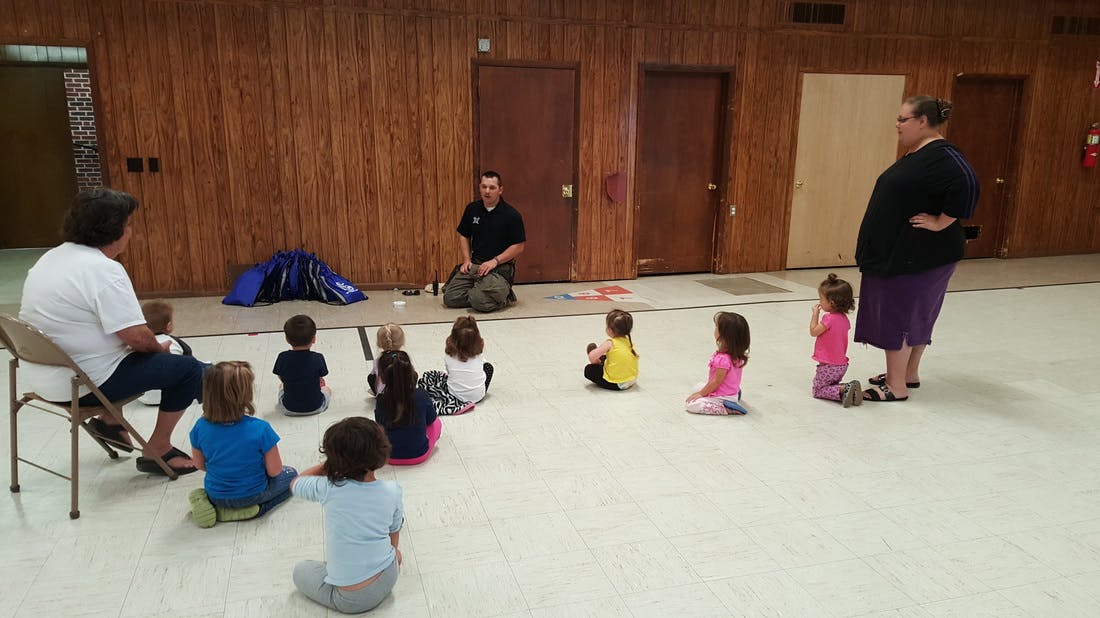 Adults and children sitting on the floor in a large room