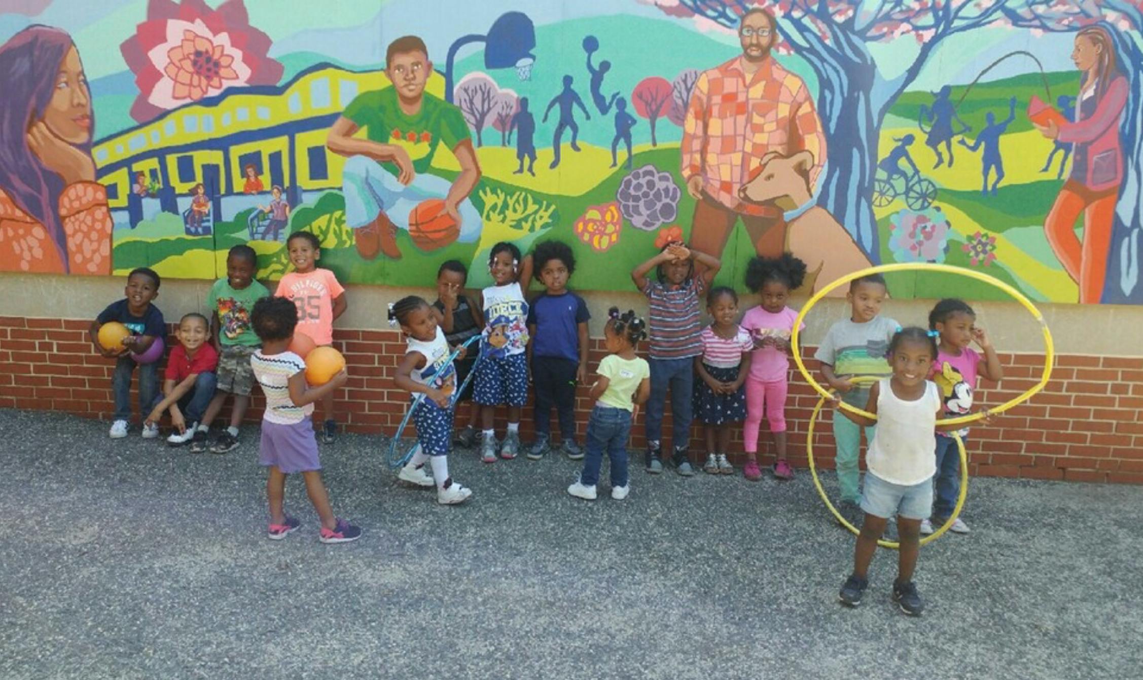 Group of children standing in front of a colorful mural