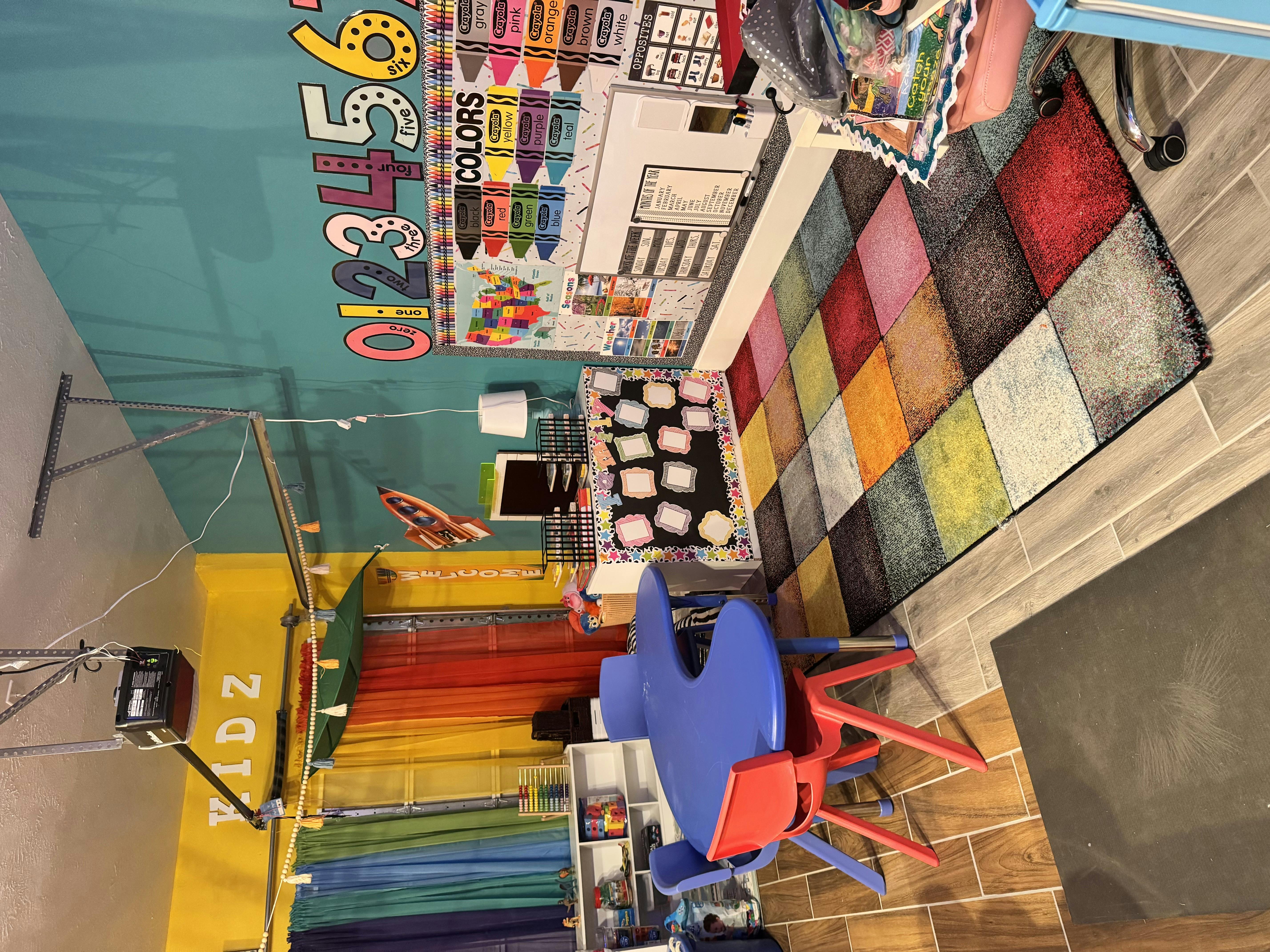 Children's play area with colorful rug, table, and wall decorations