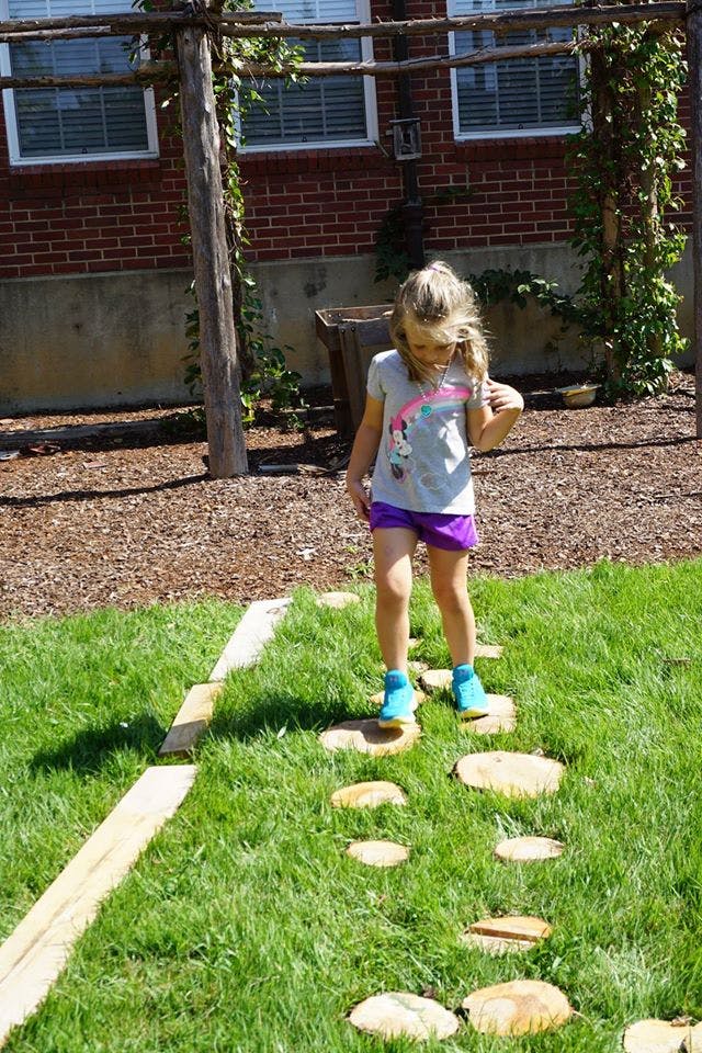 Child walking on stepping stones in grass