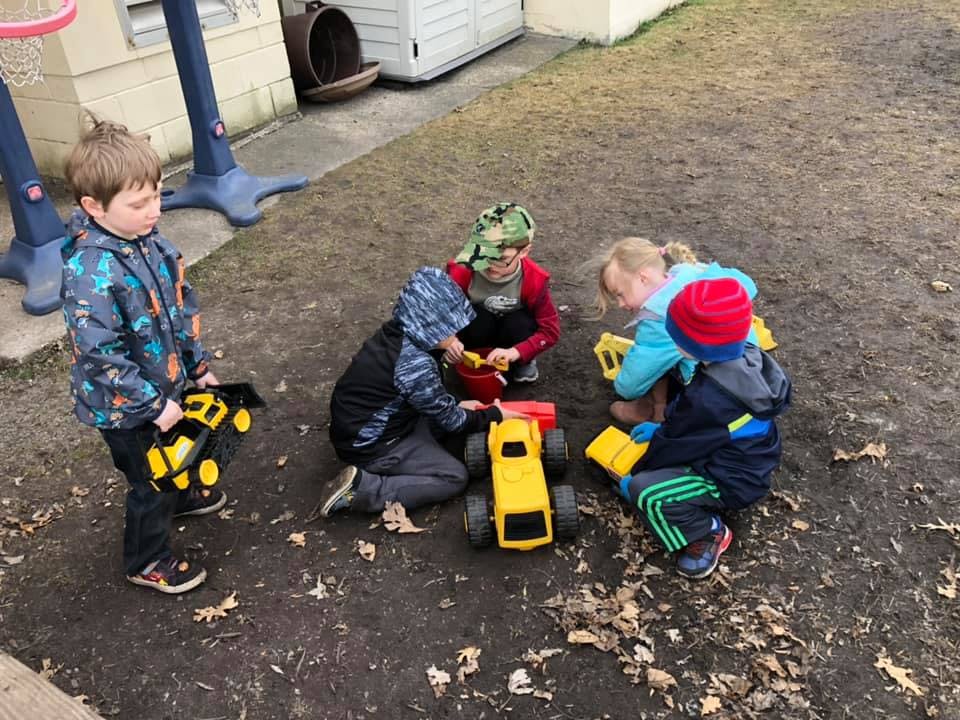 Children playing with toy trucks outdoors