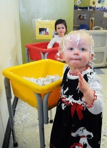 Child with shredded paper on head and clothes, another child in background