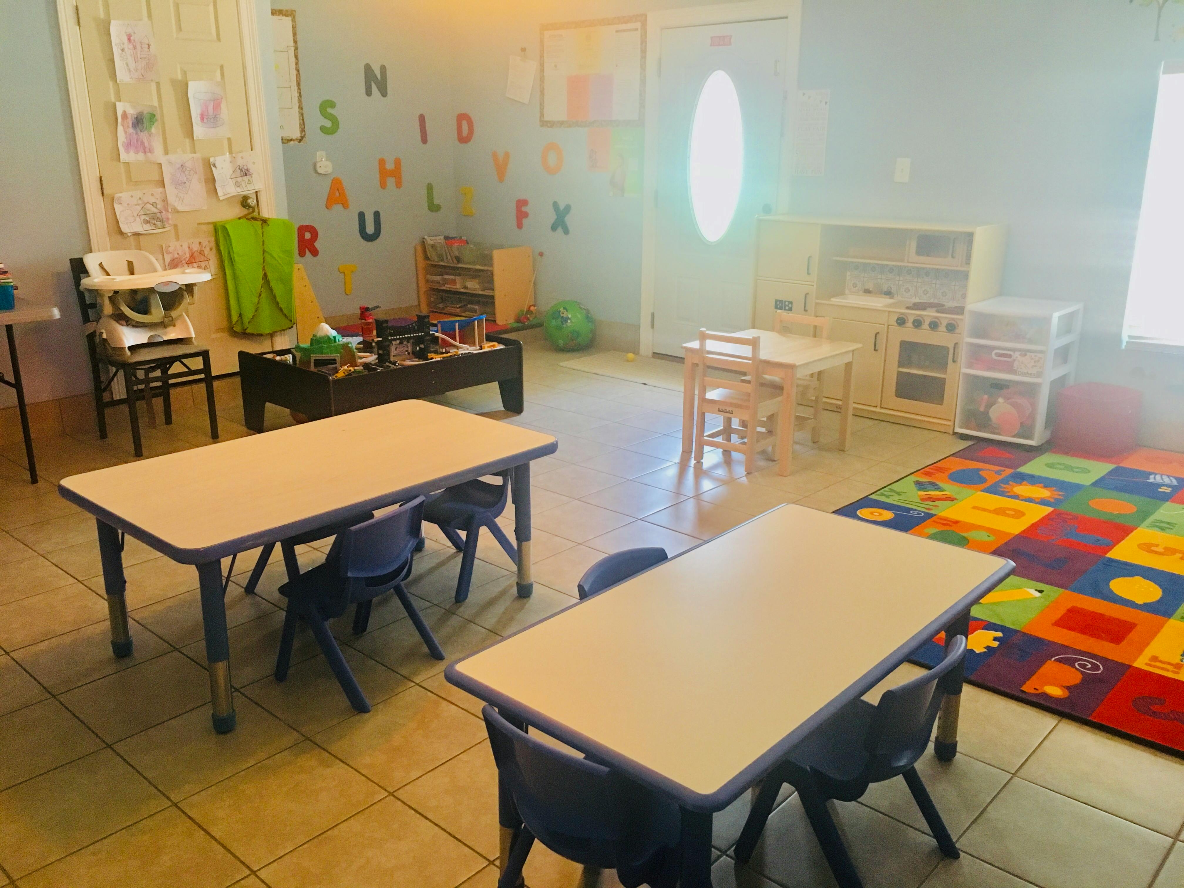 Classroom with small tables and chairs, alphabet letters on wall