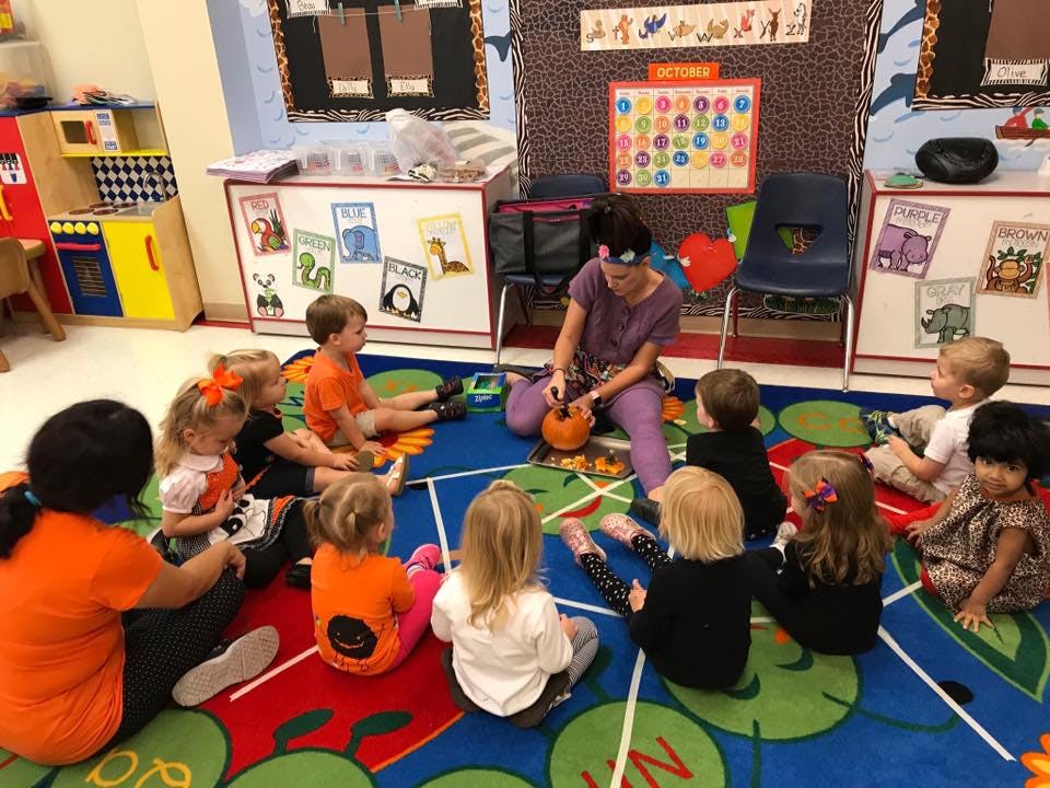 Adult and children sitting on a rug in a classroom