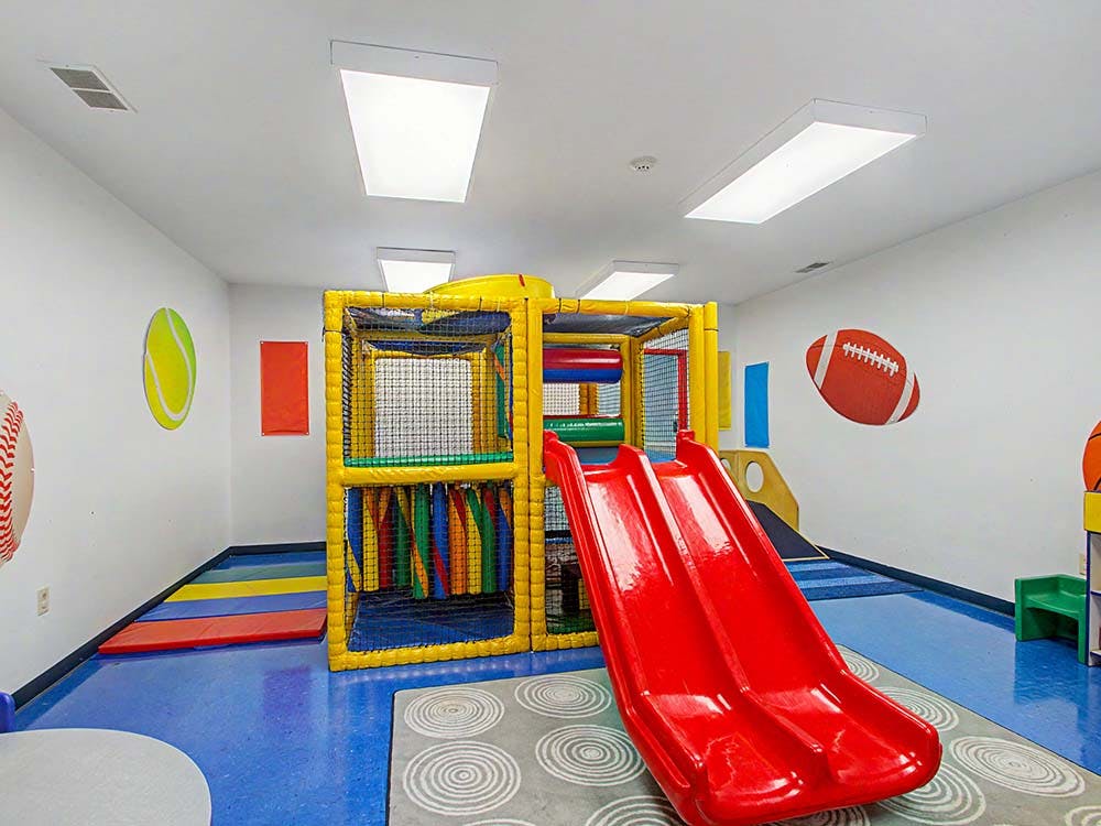 Indoor playground with yellow climbing structure and red slide