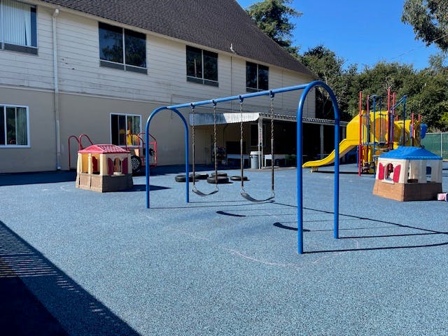 Playground with swings, slide, and playhouses on a blue surface