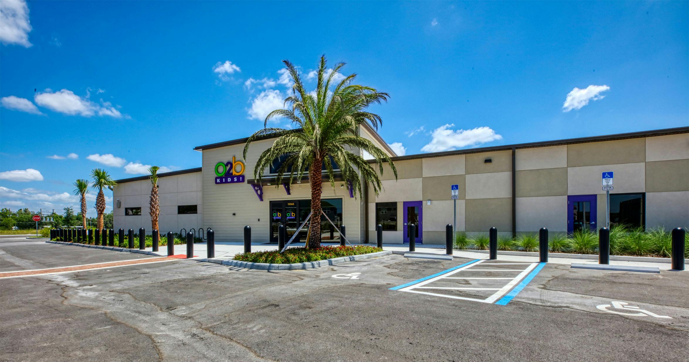 O2B Kids building exterior with parking lot and palm trees under a blue sky