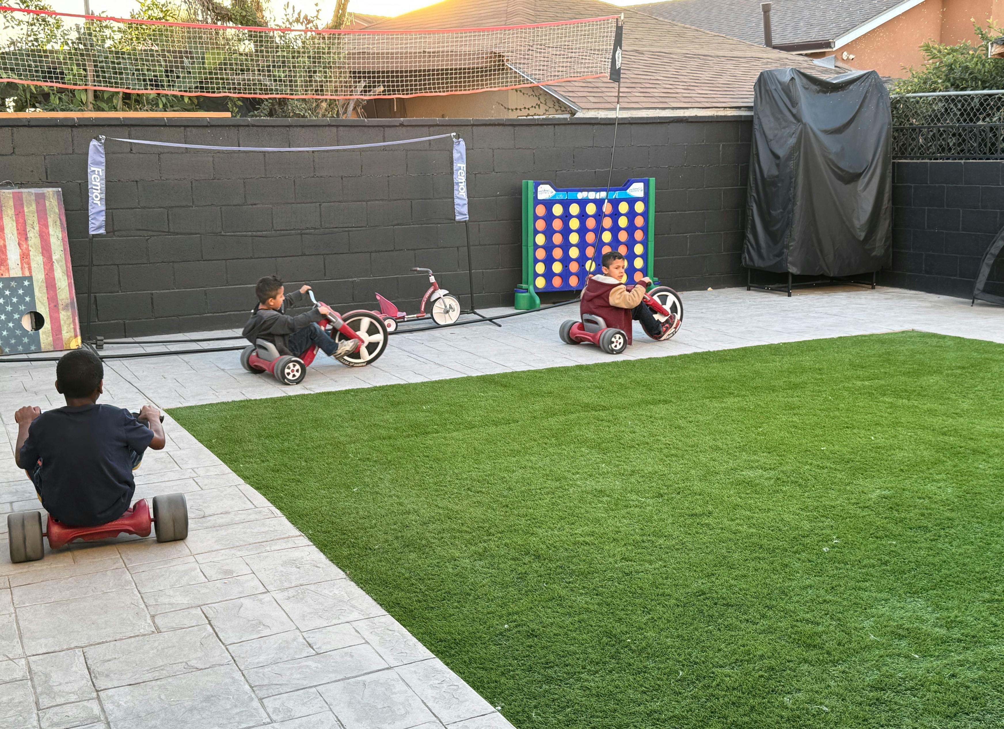 Children playing with ride-on toys in a backyard