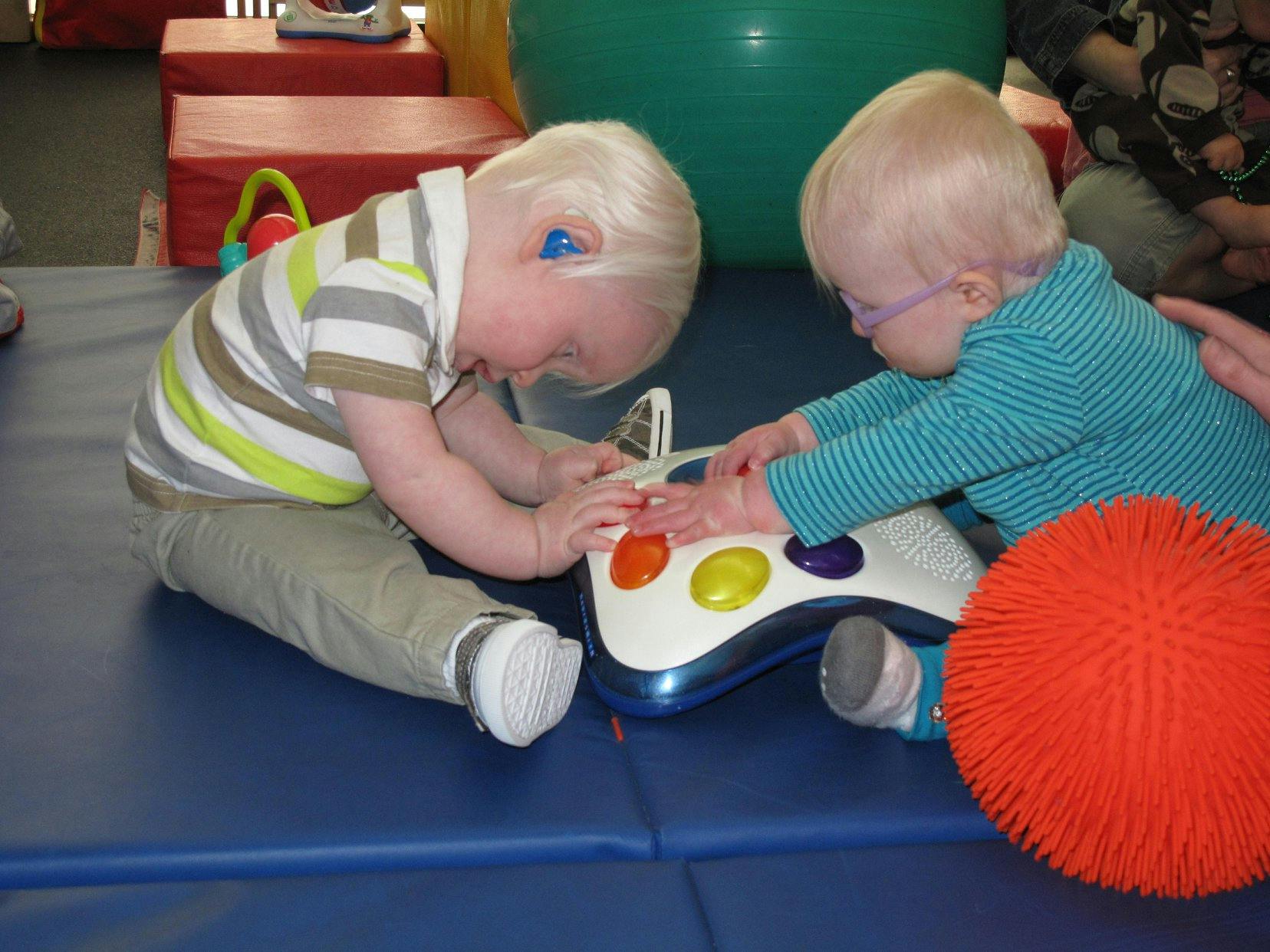 Two children playing with a light-up toy on a blue mat