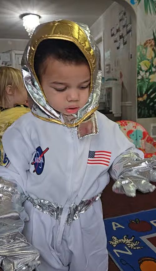 Child wearing an astronaut costume with NASA and American flag patches