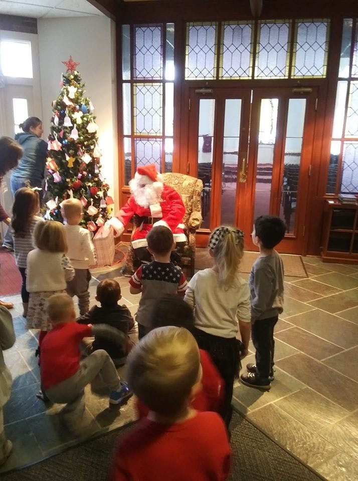 Santa Claus sitting in a chair with children gathered around him