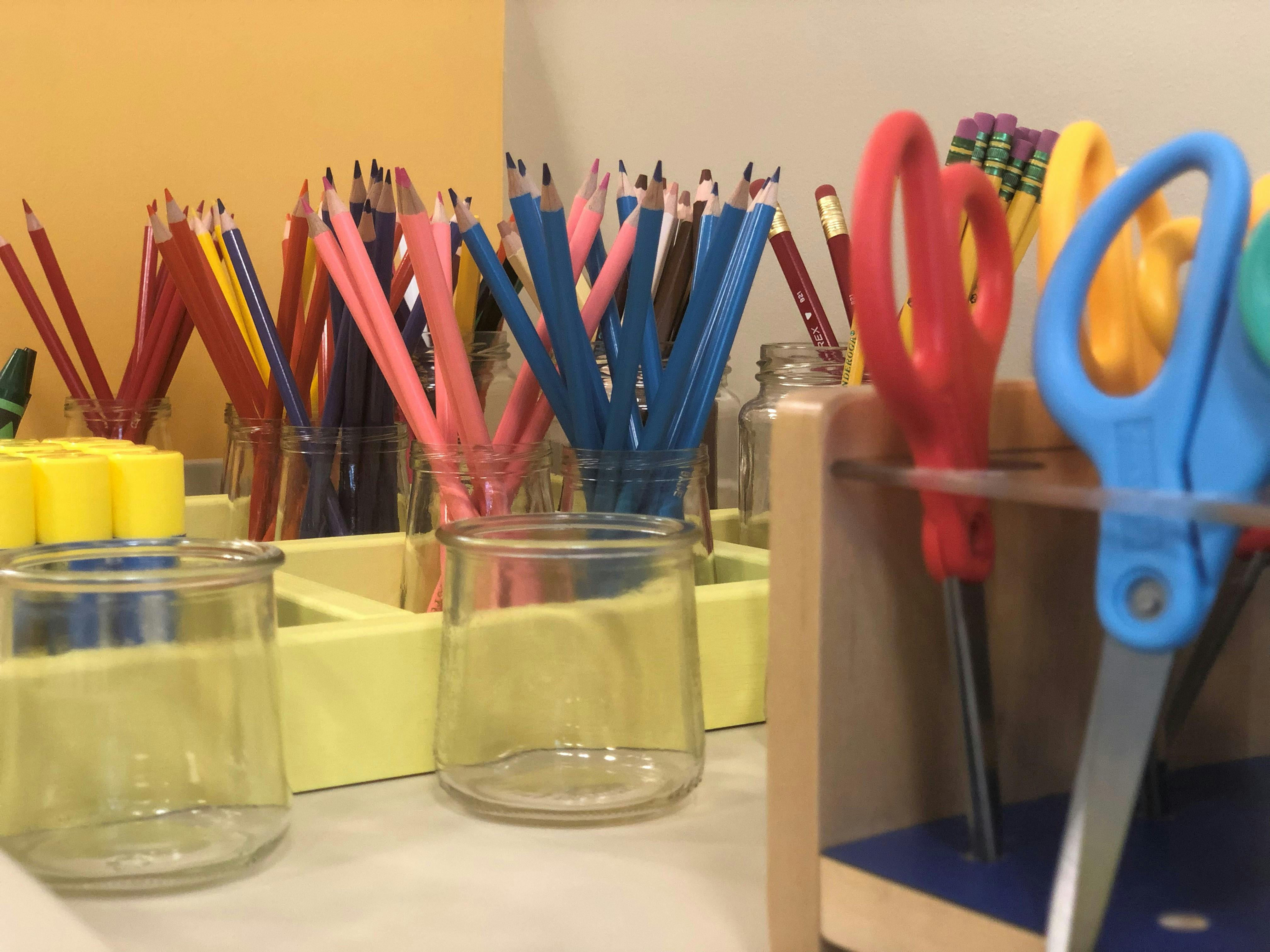 Jars of colored pencils and scissors in a classroom
