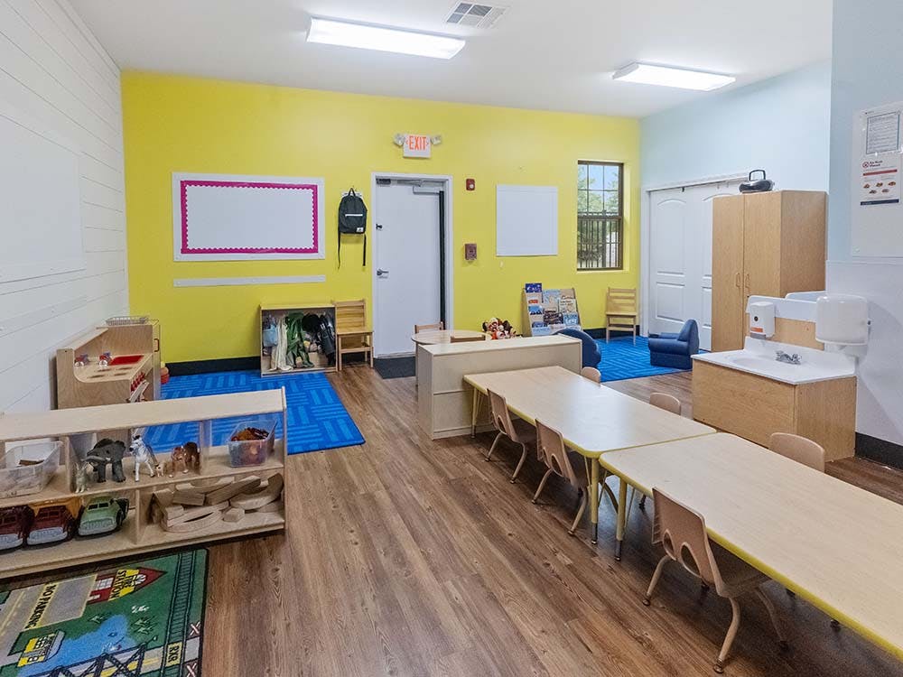 Classroom with small tables and chairs, toys, and a sink