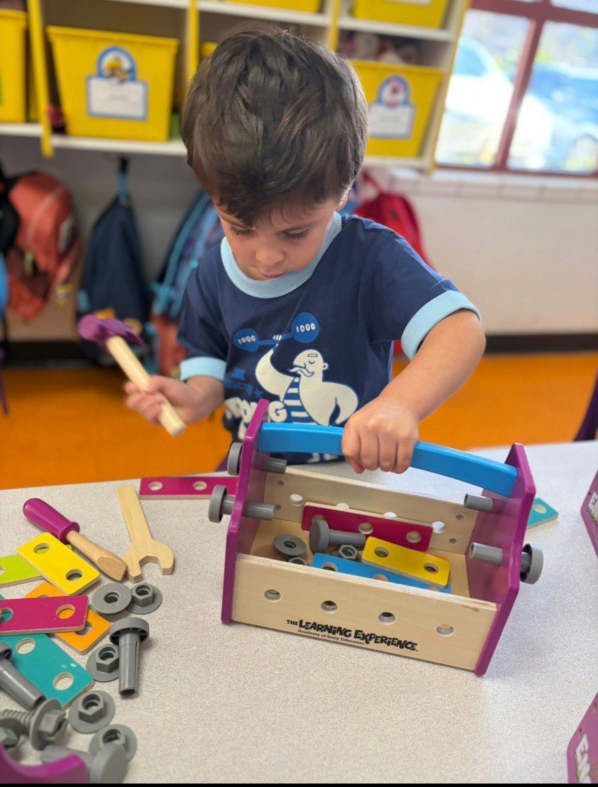 Child playing with a toy toolbox, holding a toy hammer