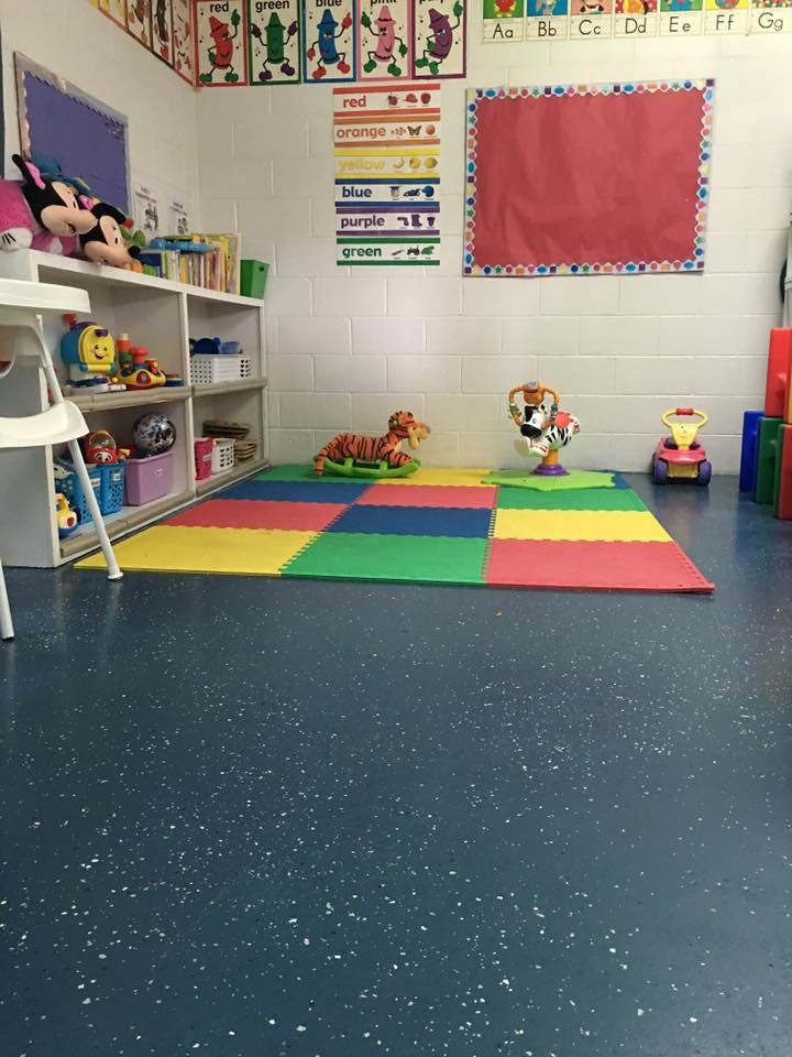 Classroom with colorful floor mats, shelves of toys, and wall decorations
