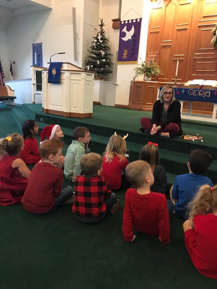Person sitting on floor with children in front of a podium
