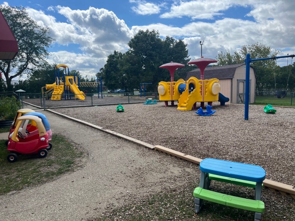 Outdoor playground with slides, swings, and ride-on toys on wood chips