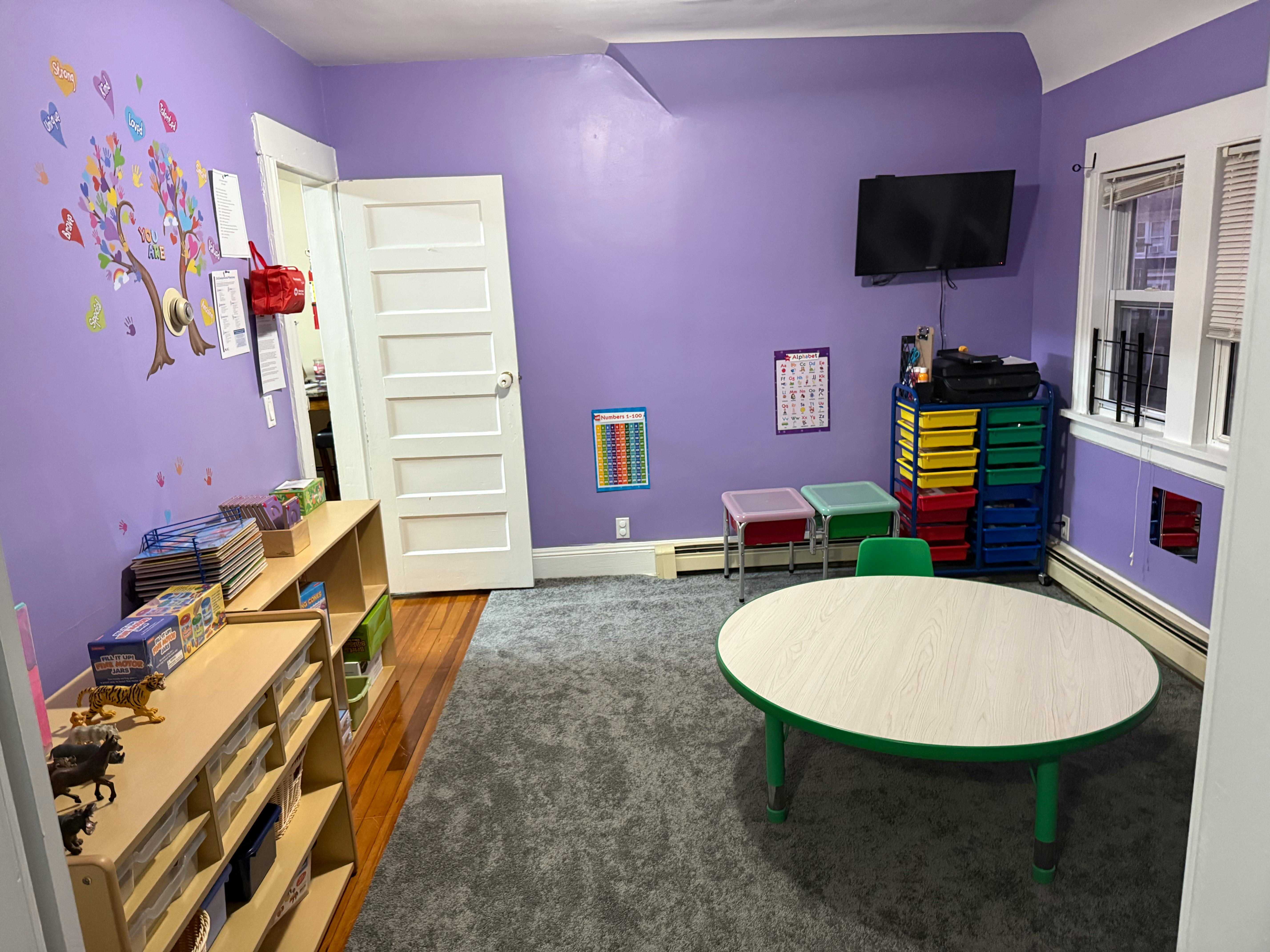 Playroom with purple walls, a small table, and shelves