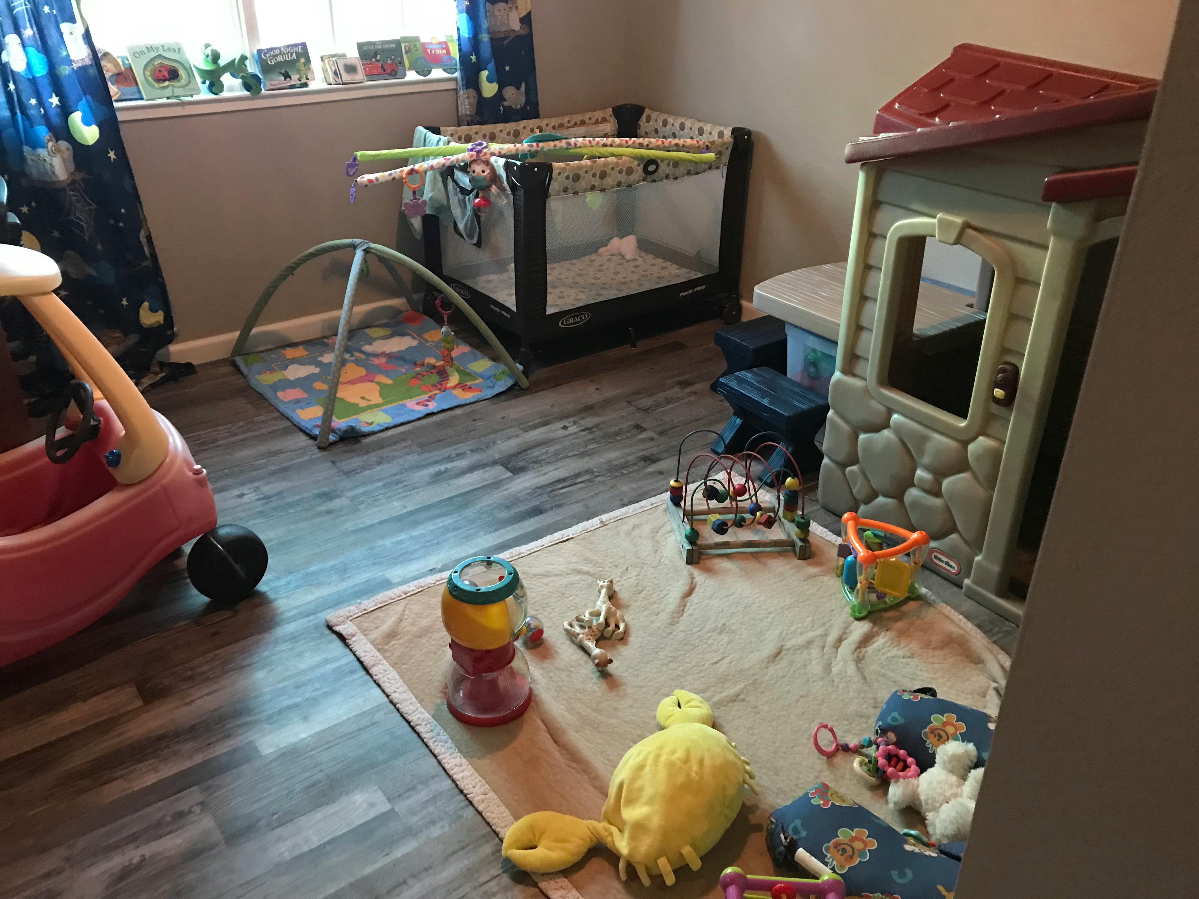 Playroom with a crib, playhouse, and various toys on the floor