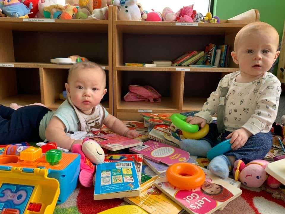 Two children playing with toys and books on the floor