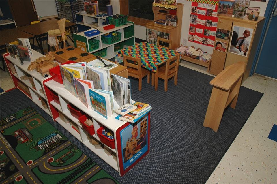 Classroom with bookshelves, a small table and chairs, and a play mat
