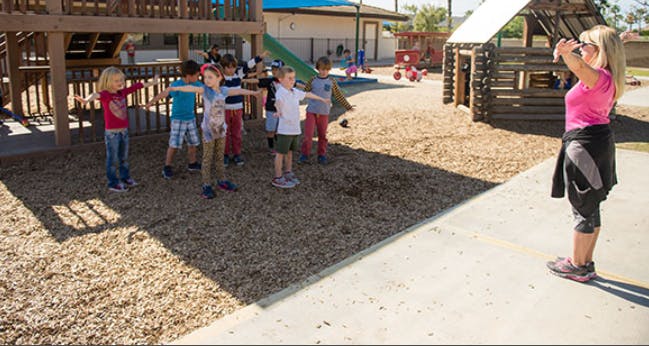 Person leading children in an exercise on a playground