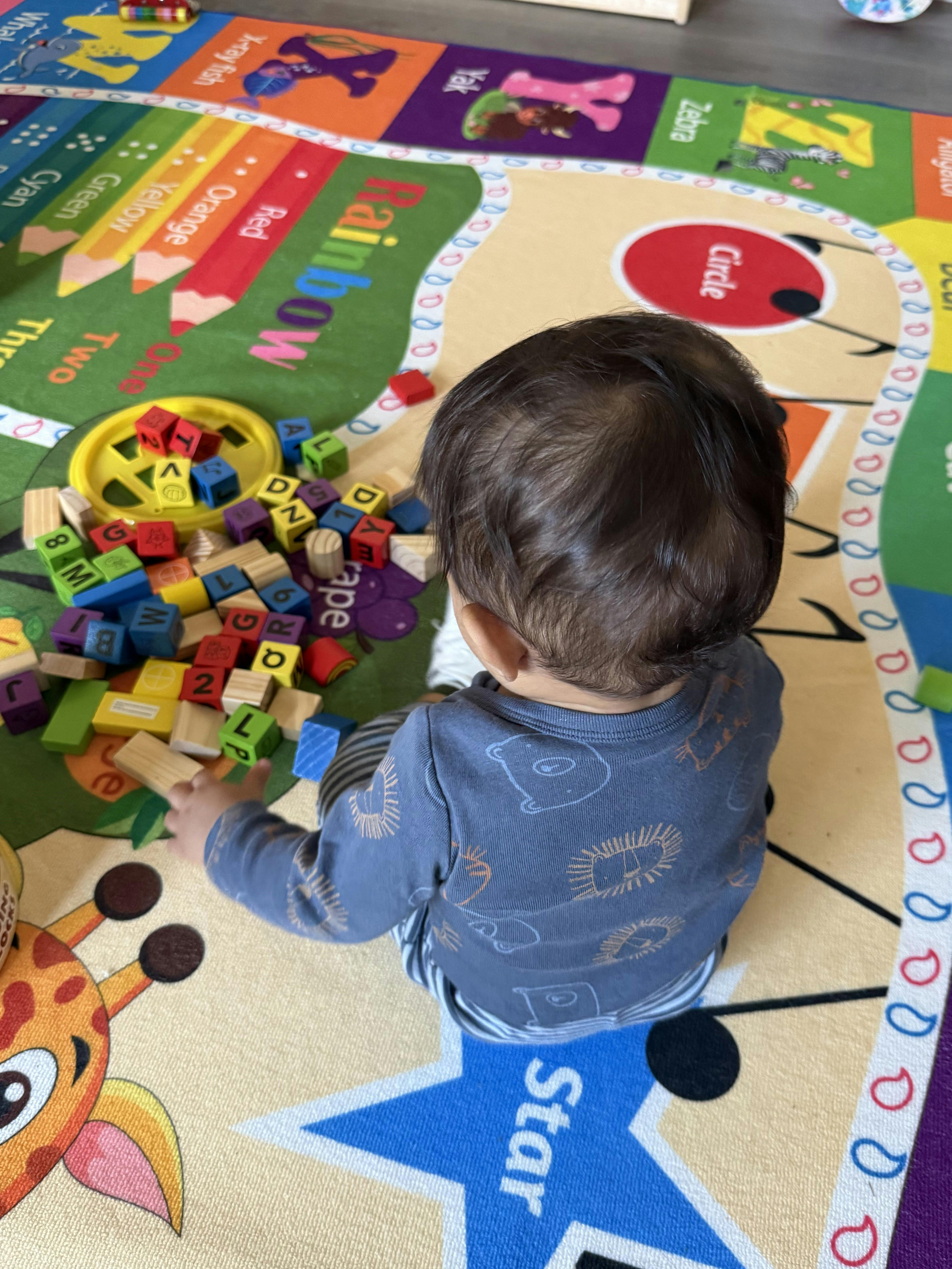 Child playing with colorful alphabet blocks on a patterned rug