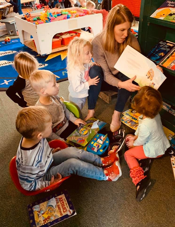 Adult reading a book to several children
